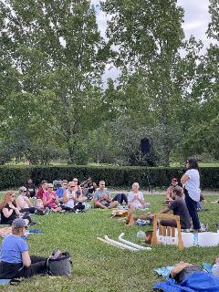 group of people sitting on blankets in a park during a sound immersion experience