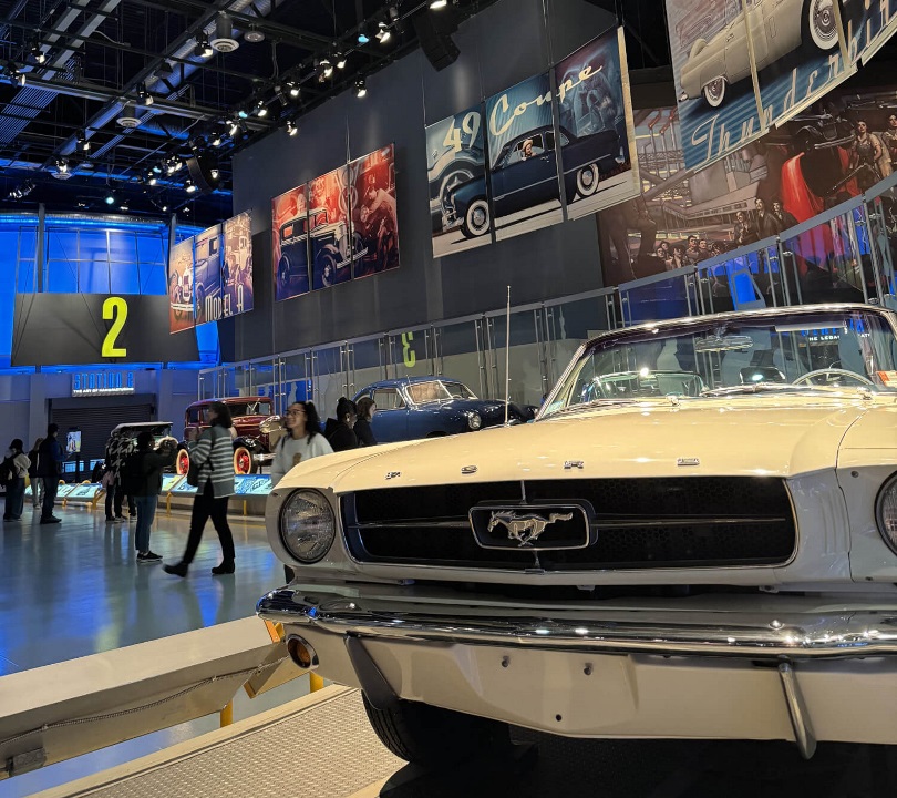 close up of ford mustang in a museum with other cars and people in the background