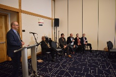 people sitting in a panel discussion at a conference