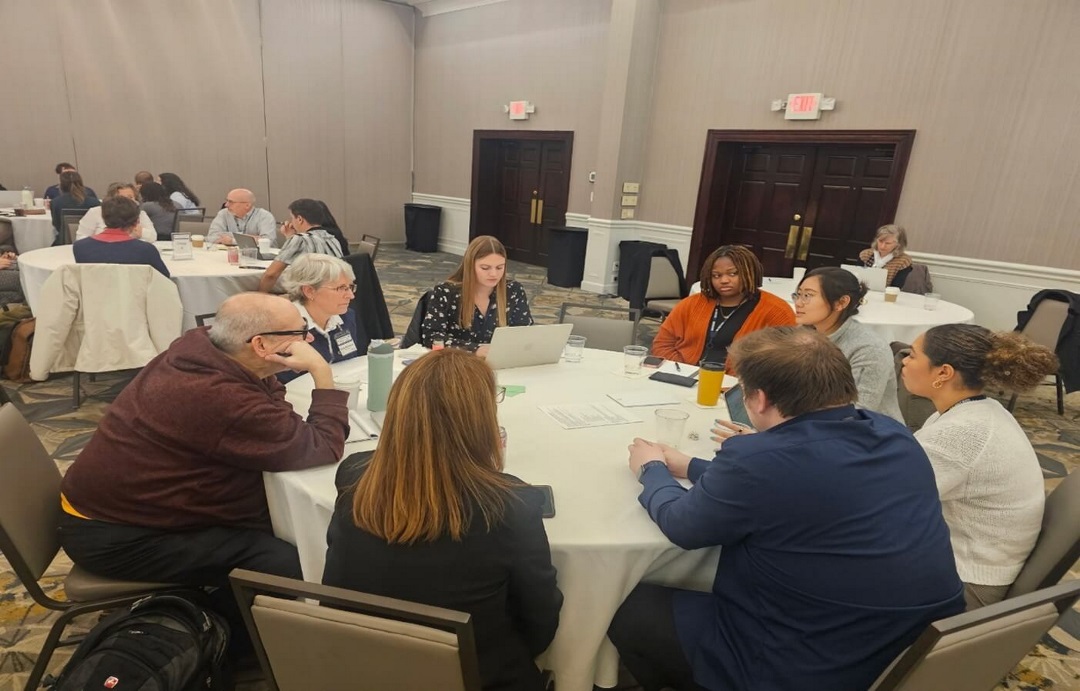 People talking at roundtables in hotel conference room