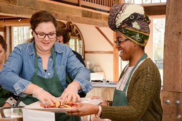 two teaching kitchen participants load a pan with healthy food