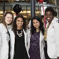 Four students in white coats pose for a photo