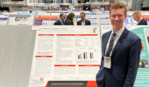 Image of Cameron Thomson MD, 2021-2022Jorge Figueras BS, 2021-2022 Orthopaedic Research Fellow presenting podium and poster at AAOS 2022 in Chicago.