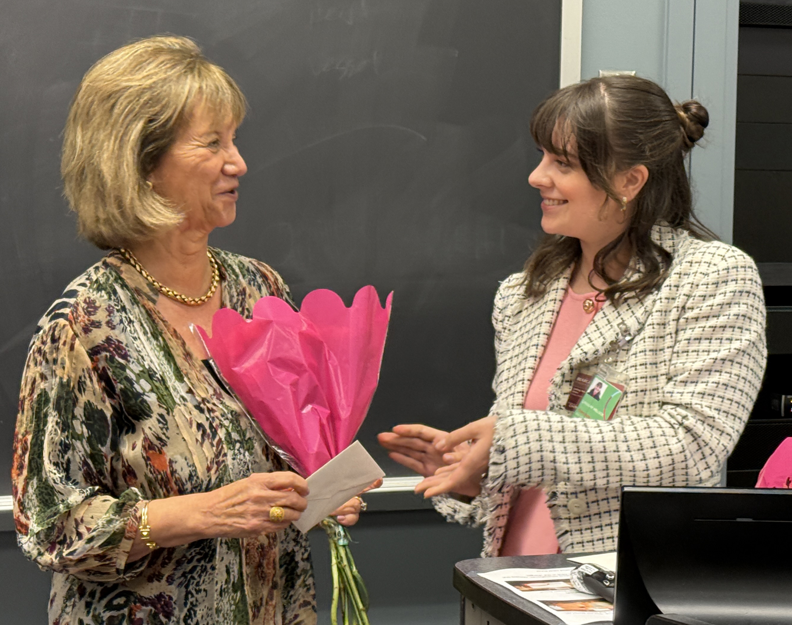 photo of Lindsay Helock handing card and flowers to Dr. Kranias